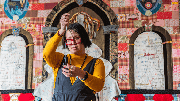 Layla working on the finishing touches of 'A Virtuous Woman' with the colourful artwork in the background